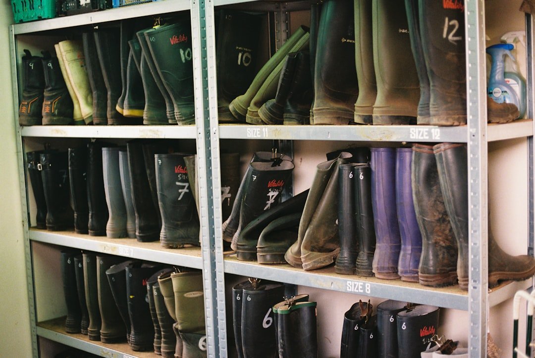 Rows of rubber wellington boots organized by size on metal storage shelves