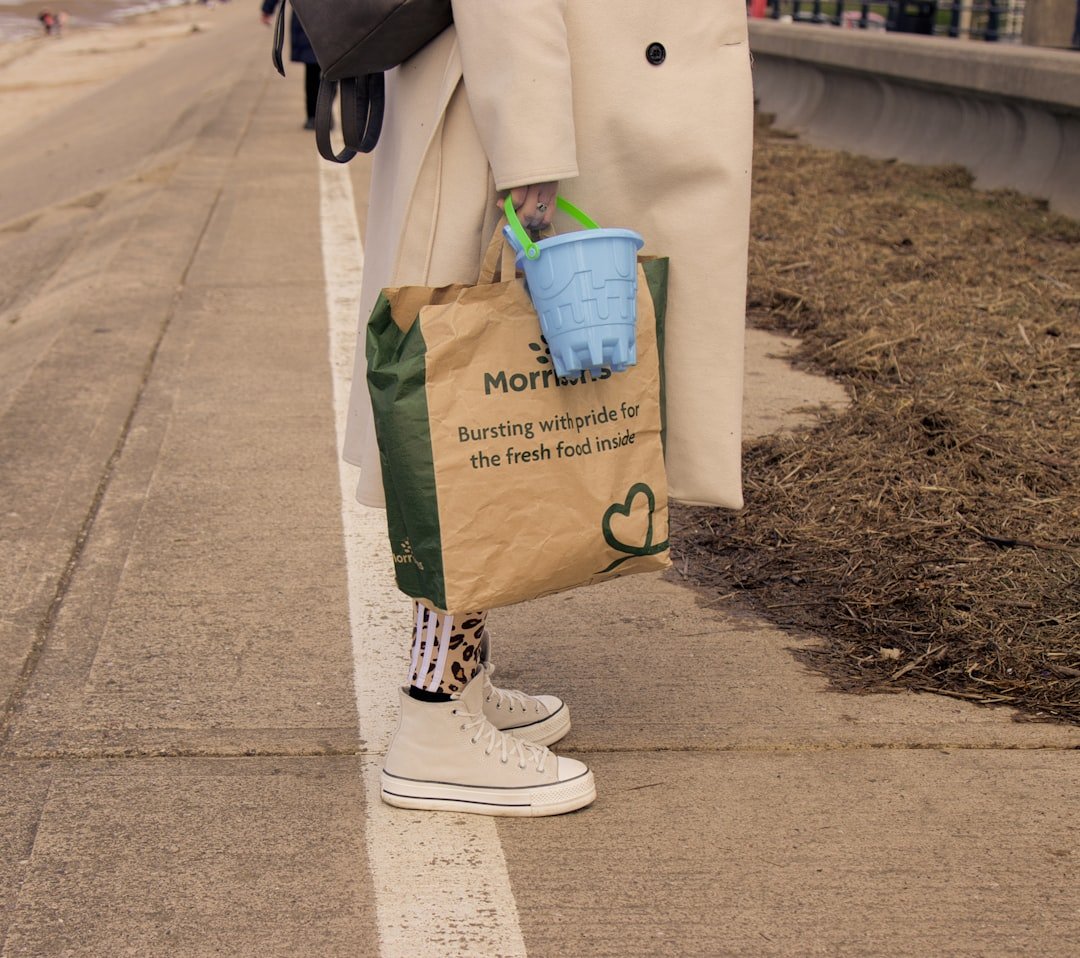 A woman standing on the side of a road holding a shopping bag